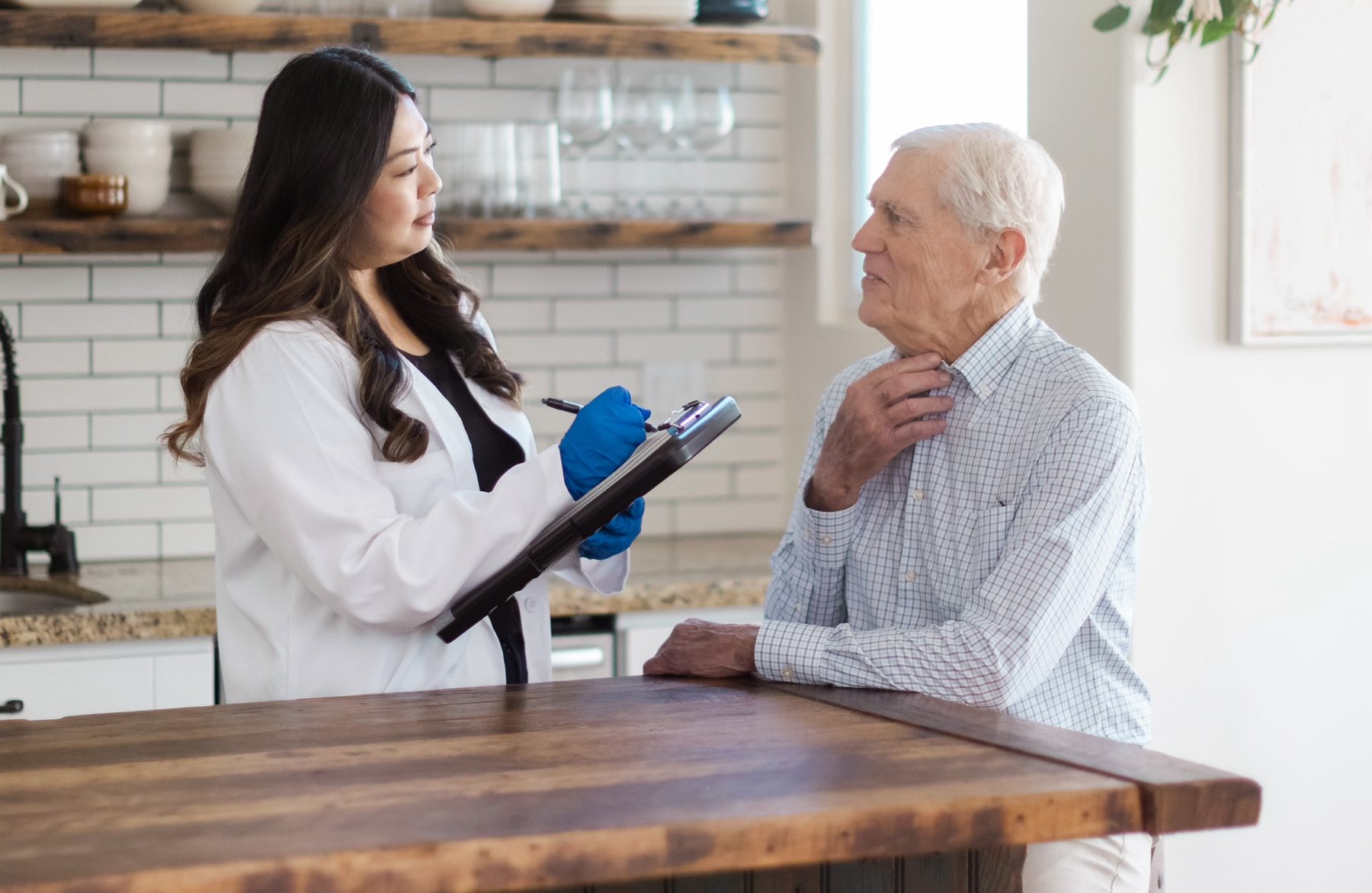 Speech-language pathologist taking notes during an in-home consultation with an older patient
